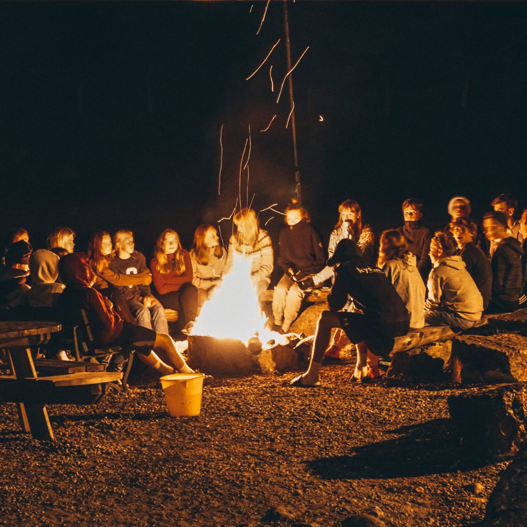 a group of people sitting around a campfire
